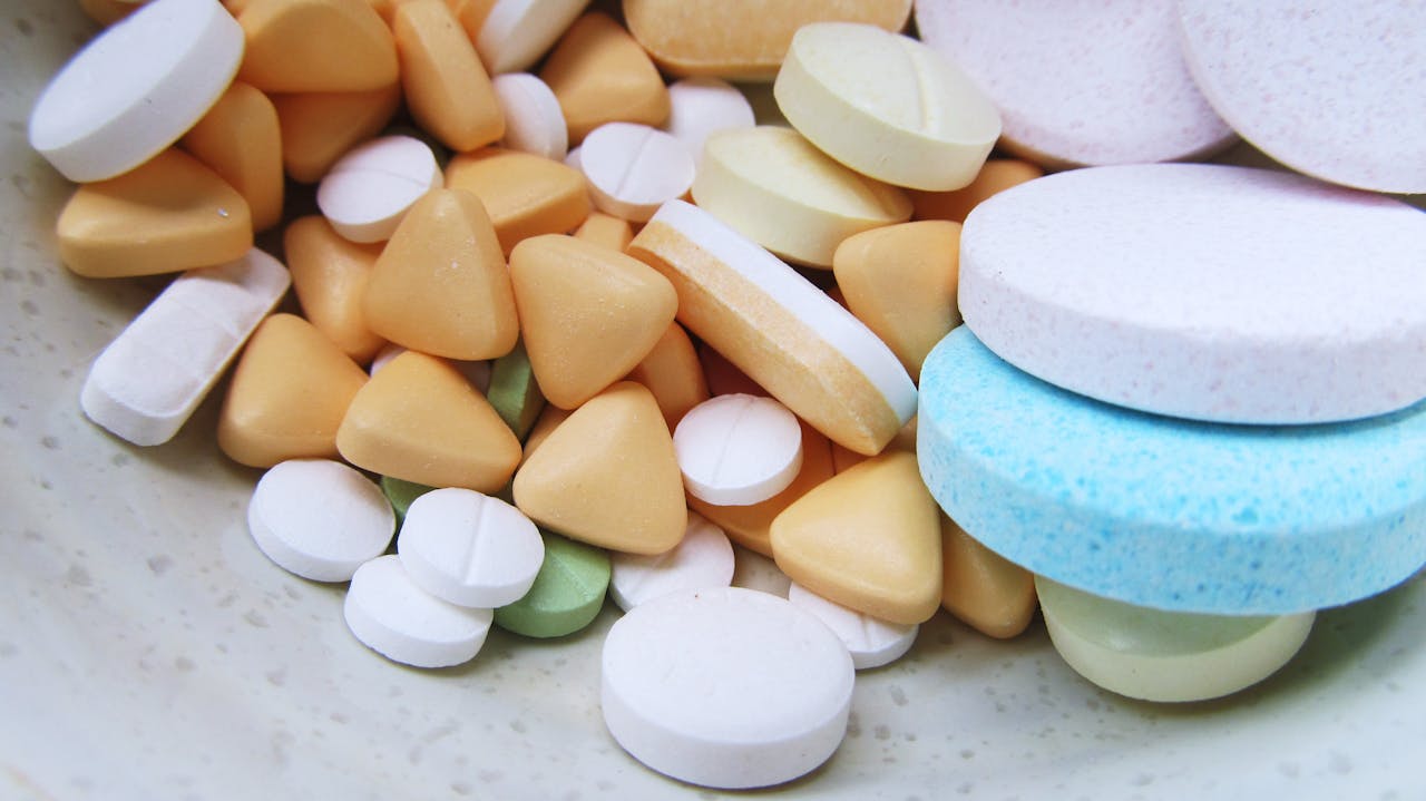 Close-up image of various colorful pills and tablets on a neutral surface.