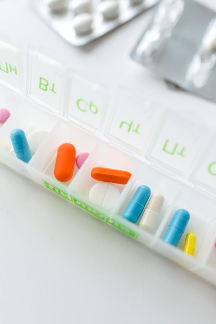 Close-up of various pills in a weekly pill organizer for daily medication management.